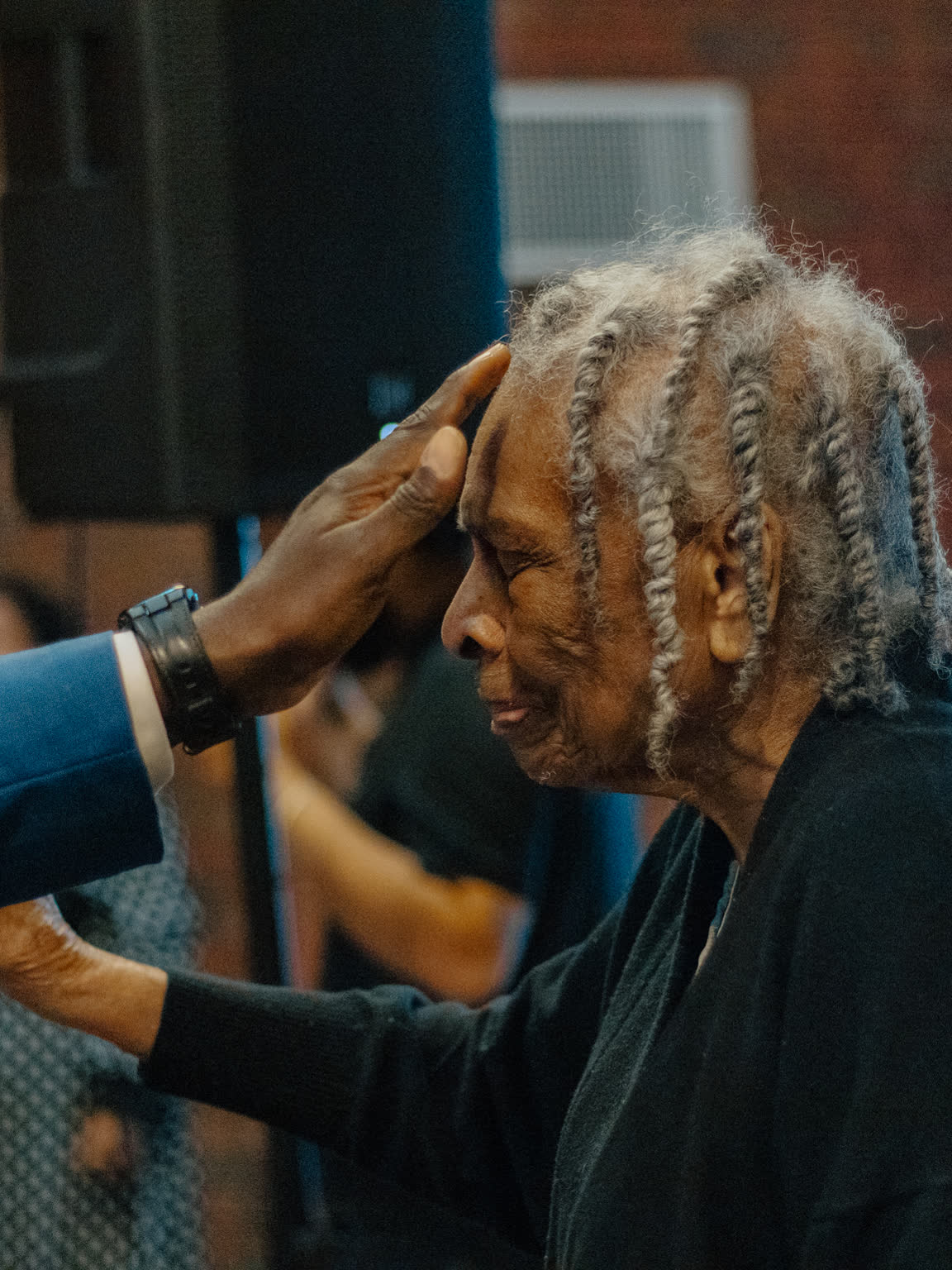 An elder receiving prayer with a hand on her head